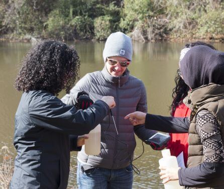 Students gathered around equipment for testing a water sample