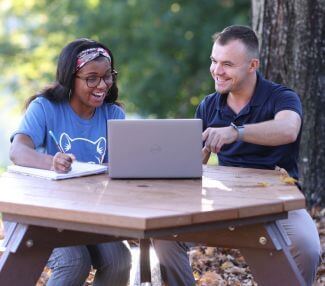 Caucasian male and african american female students in discussion at table