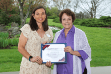 Person smiles with other person holding certificate